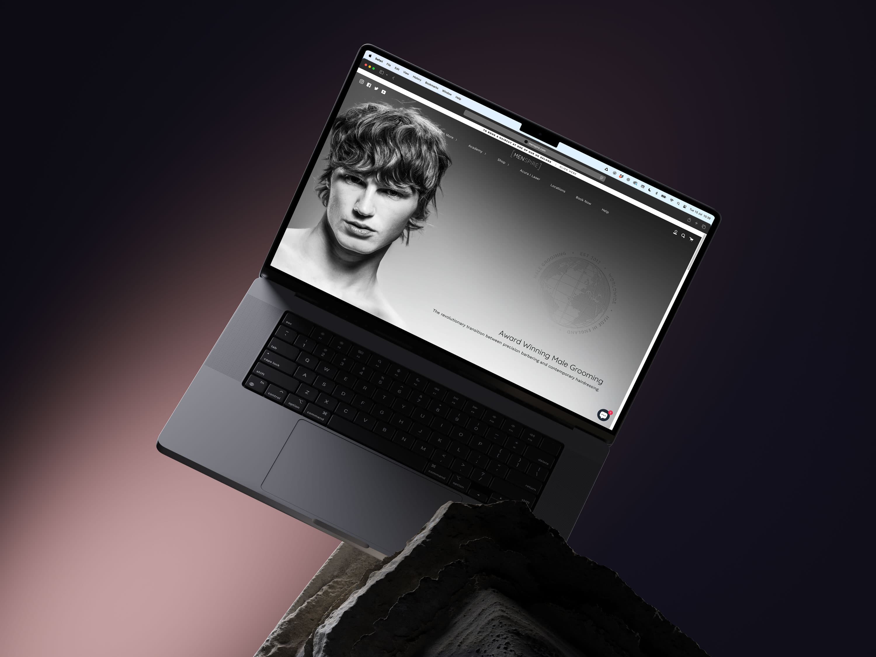 The Menspire website displayed on a laptop set against a dark sculptural landscape.